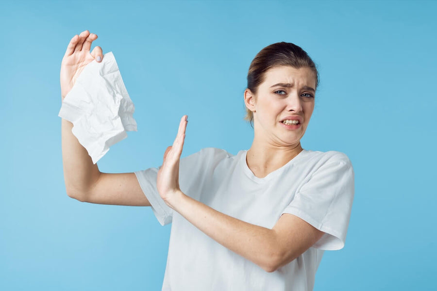 Woman recoiling from a crumpled white wipe against a blue background.