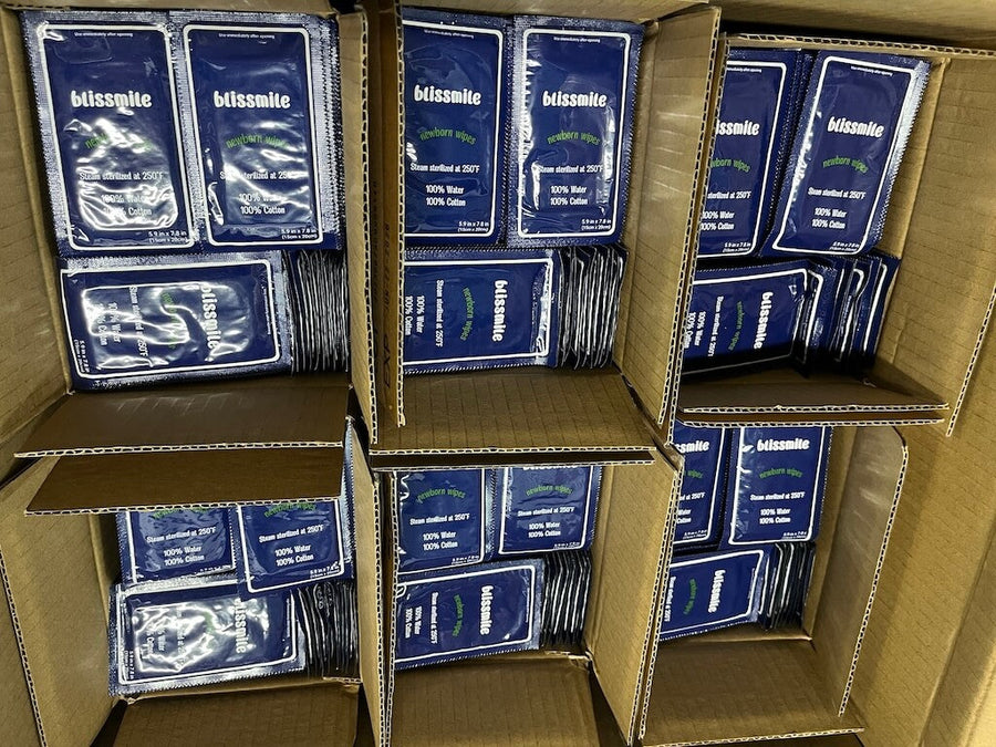 Open cardboard cartons filled with individually wrapped Blissmile wipes.