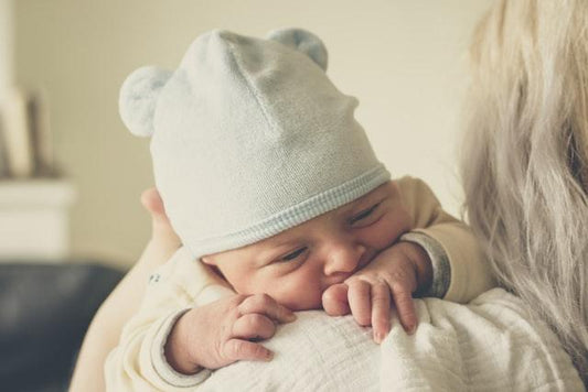 parent hugging a baby with a hat
