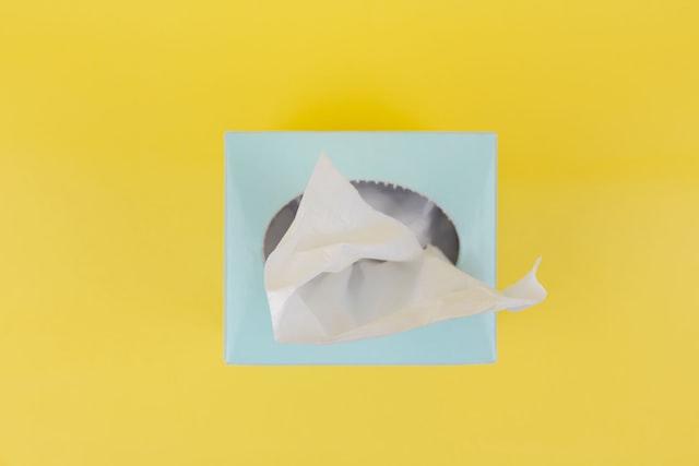 White wipe pulled from a light blue dispenser against a yellow background.
