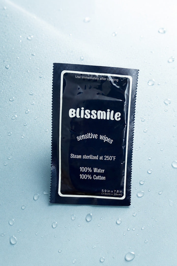 Individually wrapped navy Blissmile Sensitive Wipe on a water-beaded surface